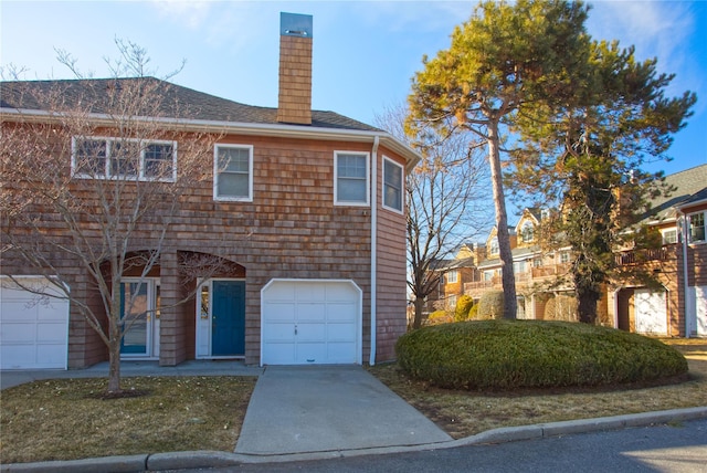 view of front of property with driveway, a shingled roof, a chimney, and an attached garage