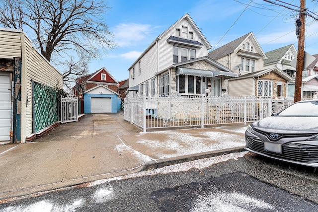 view of front of home featuring a garage, a residential view, concrete driveway, and an outbuilding