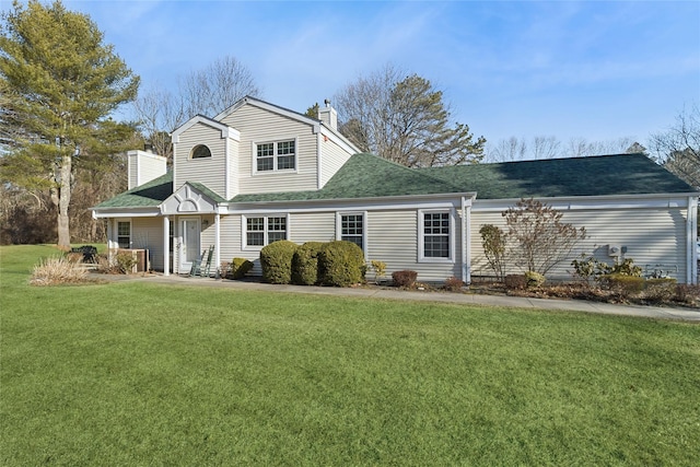 view of front of home with roof with shingles, a front lawn, and a chimney