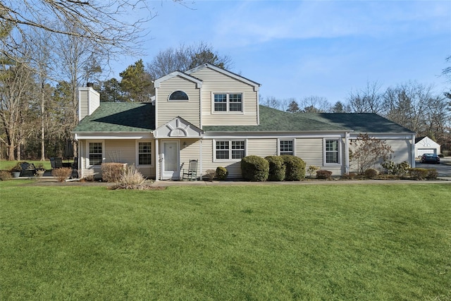 view of front of property with roof with shingles, a chimney, and a front lawn