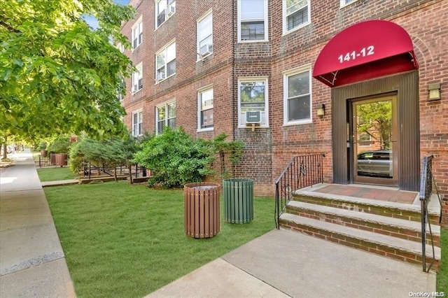 view of exterior entry with brick siding and a yard