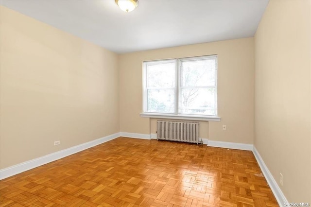 spare room featuring radiator and baseboards