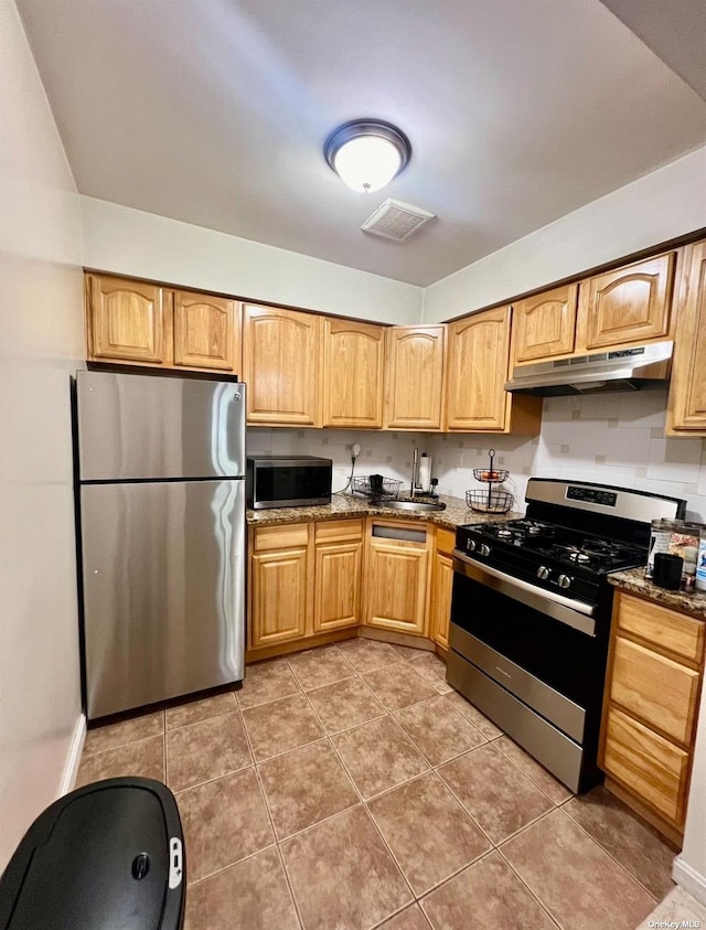 kitchen with stainless steel appliances, visible vents, tile patterned flooring, dark stone counters, and under cabinet range hood