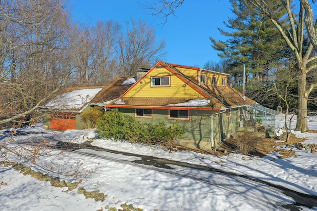 snow covered property featuring a chimney and a greenhouse