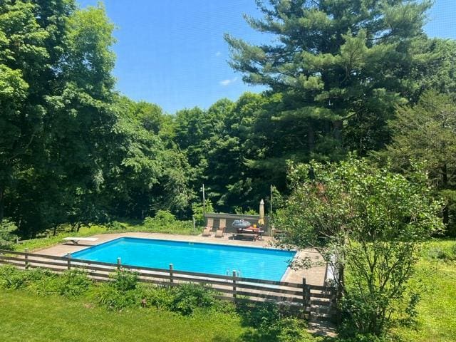 pool featuring a diving board, a patio, and fence