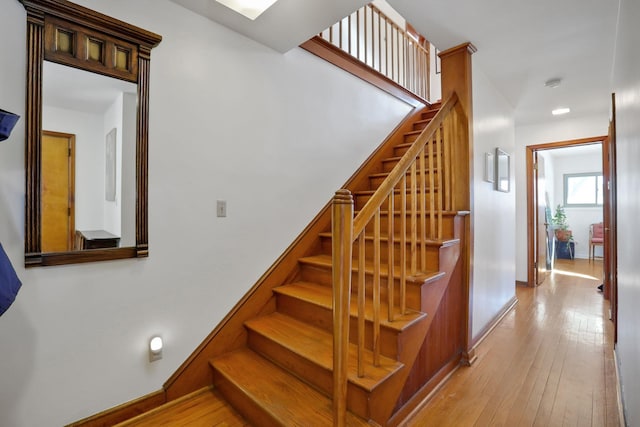 staircase featuring baseboards and wood finished floors