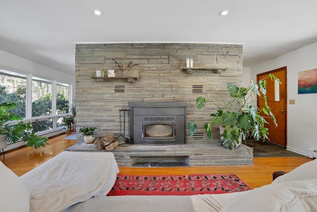 living room featuring a stone fireplace, wood finished floors, and recessed lighting