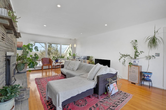 living area with light wood-style floors, a baseboard radiator, a brick fireplace, and recessed lighting