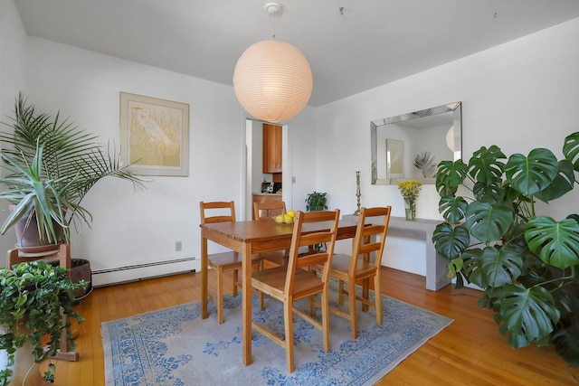 dining space featuring a baseboard heating unit and light wood-style floors