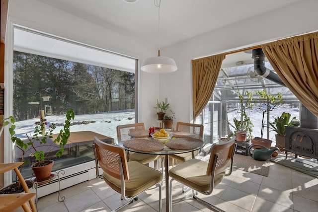 dining room with a wood stove, baseboard heating, and light tile patterned flooring