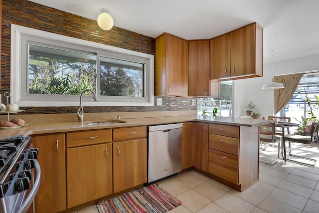 kitchen with decorative backsplash, brown cabinets, a peninsula, stainless steel appliances, and a sink