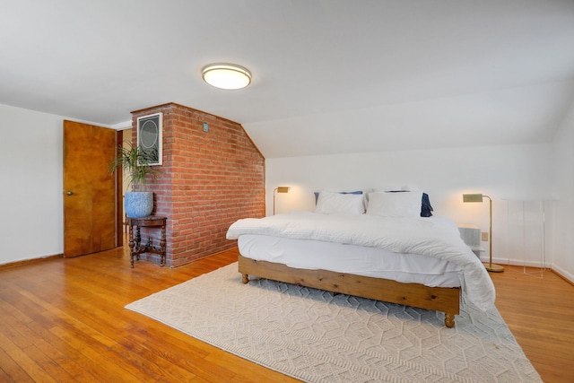 bedroom with lofted ceiling, baseboards, and wood finished floors