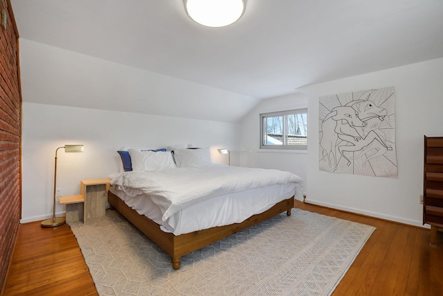 bedroom featuring light wood-type flooring, baseboards, and lofted ceiling