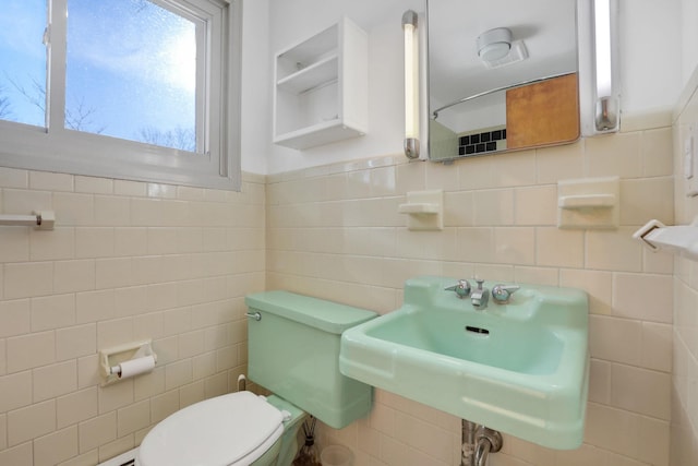 bathroom featuring a sink, tile walls, and toilet