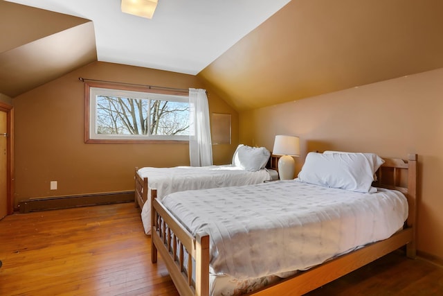 bedroom with vaulted ceiling, baseboard heating, wood finished floors, and baseboards