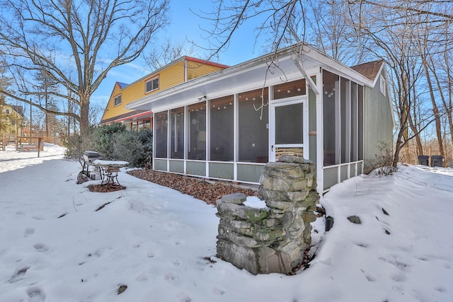 view of snowy exterior with a garage and a sunroom