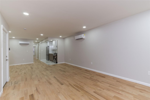 unfurnished living room with baseboards, an AC wall unit, recessed lighting, and light wood-style floors