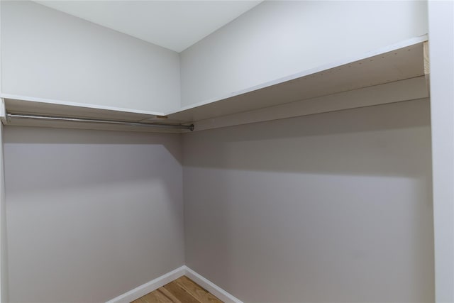 walk in closet with wood finished floors