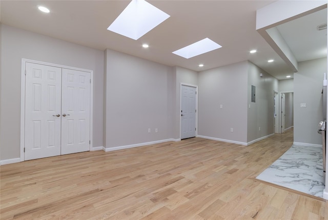 empty room featuring baseboards, recessed lighting, electric panel, and light wood-style floors