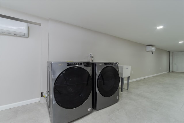 clothes washing area featuring laundry area, baseboards, washing machine and clothes dryer, and a wall mounted air conditioner