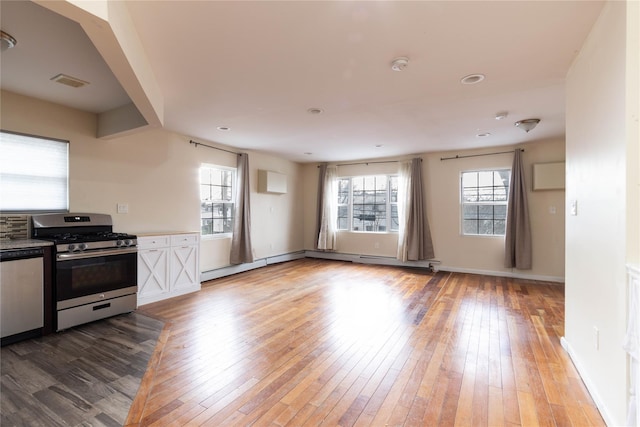 kitchen featuring a baseboard radiator, hardwood / wood-style flooring, visible vents, appliances with stainless steel finishes, and a wall mounted AC