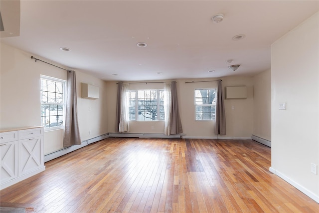 unfurnished room featuring baseboard heating, a baseboard radiator, light wood-style flooring, and baseboards