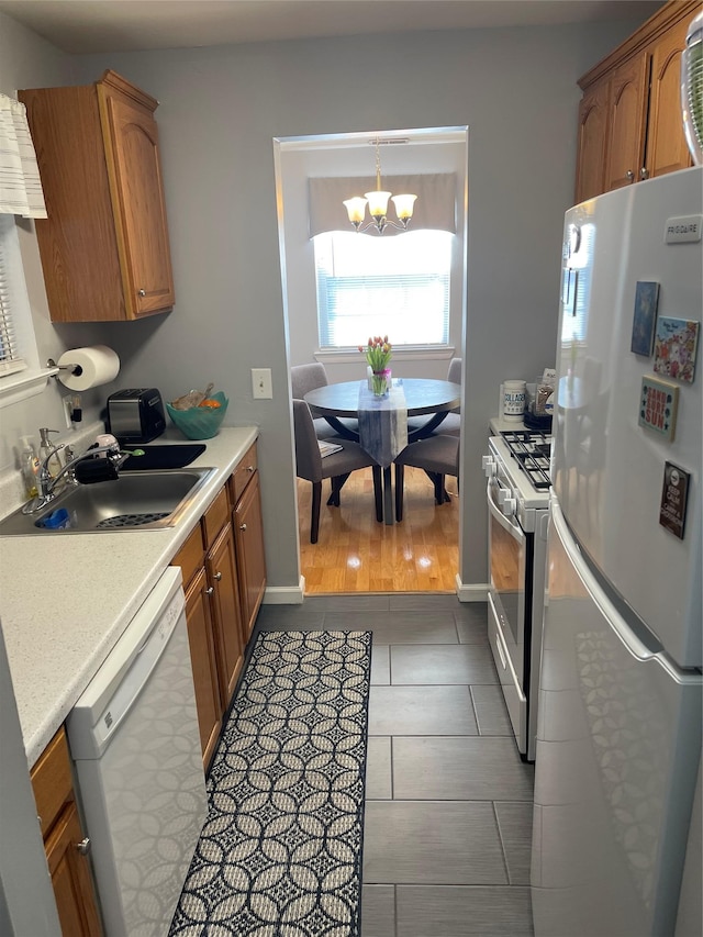 kitchen featuring light countertops, white appliances, brown cabinets, and a sink