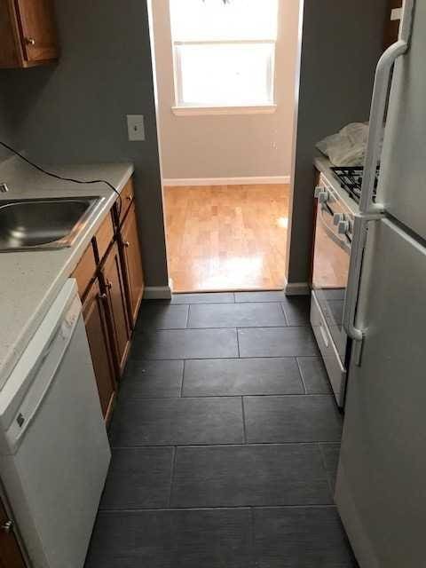 kitchen featuring white appliances, dark wood-type flooring, a sink, light countertops, and brown cabinets