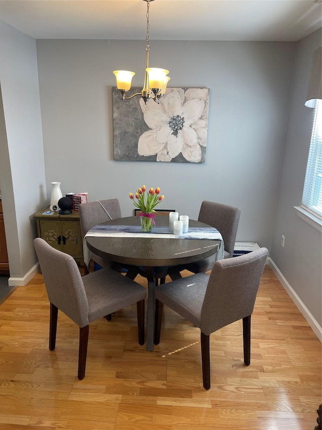 dining room with baseboards, light wood-type flooring, and an inviting chandelier