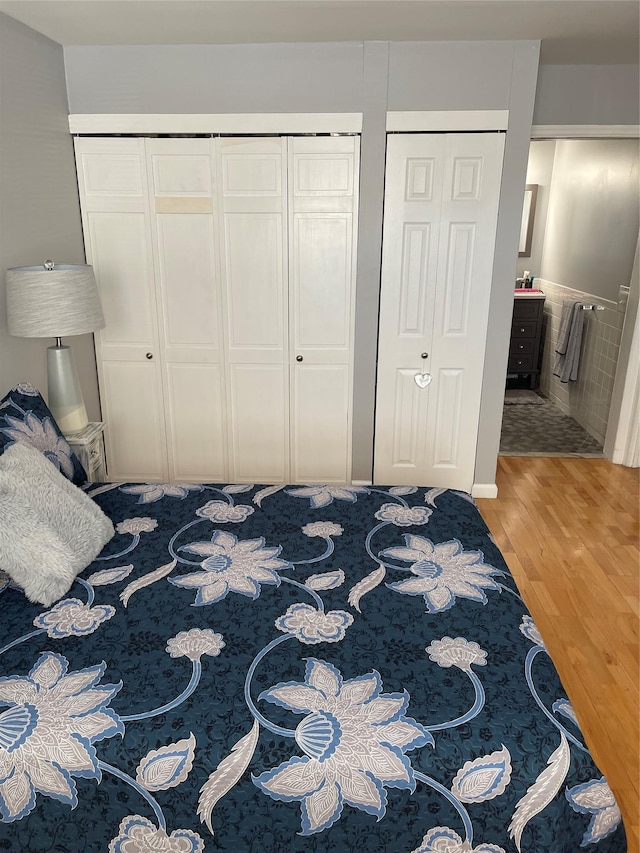 bedroom featuring radiator, ensuite bath, and wood finished floors