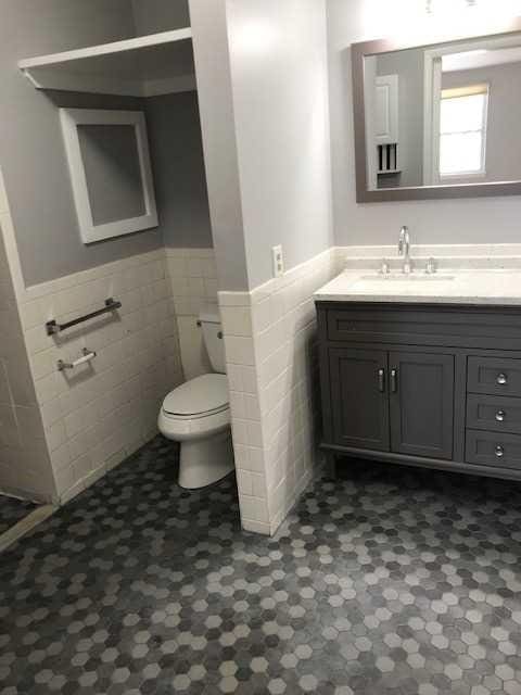 bathroom featuring toilet, a wainscoted wall, tile walls, and vanity