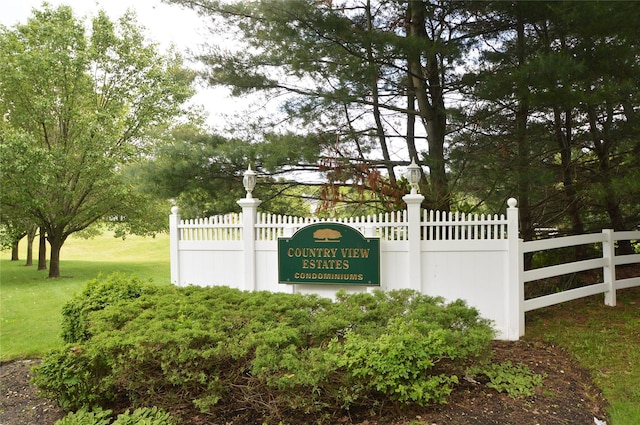 community / neighborhood sign with a yard and fence