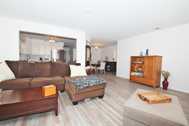 living room with a toaster, light wood-type flooring, visible vents, and a ceiling fan