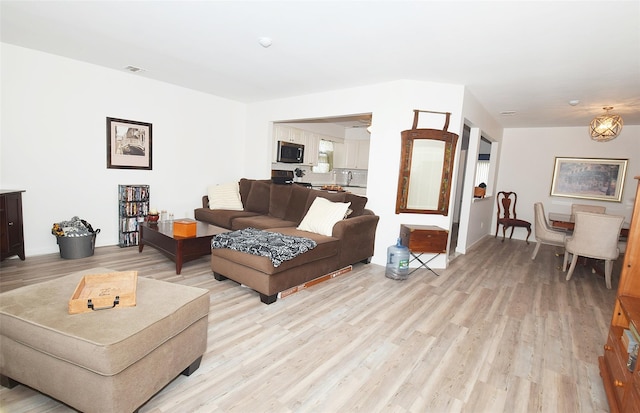 living area featuring light wood-type flooring and visible vents