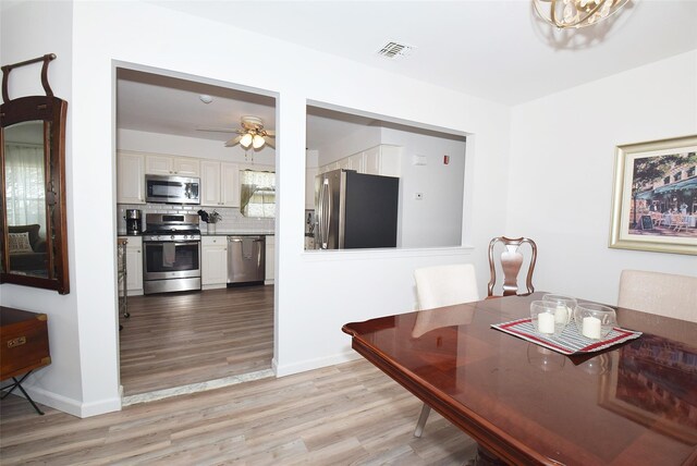 dining space with baseboards, light wood-style flooring, visible vents, and a ceiling fan