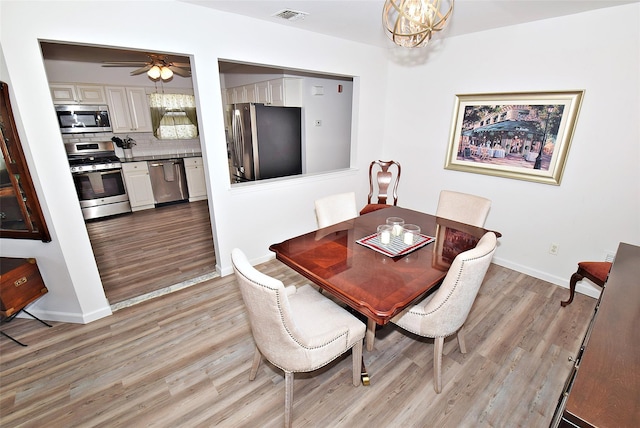 dining space featuring baseboards, ceiling fan with notable chandelier, visible vents, and light wood-style floors