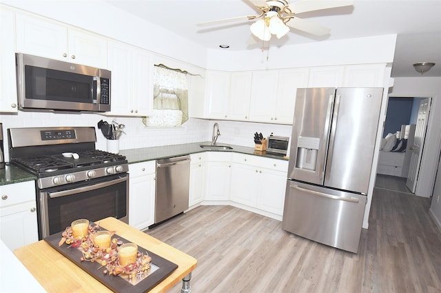 kitchen with dark countertops, light wood finished floors, stainless steel appliances, and a sink