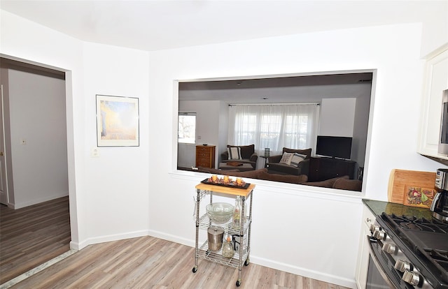 kitchen featuring dark countertops, gas stove, light wood-style flooring, and baseboards