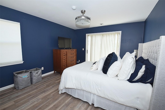 bedroom with visible vents, baseboards, and wood finished floors