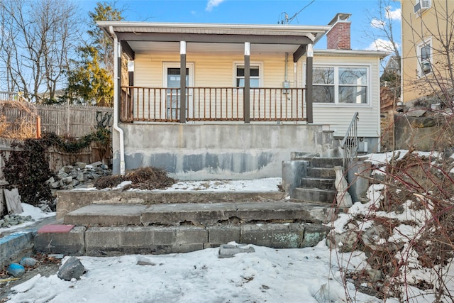 bungalow featuring covered porch, a chimney, and fence