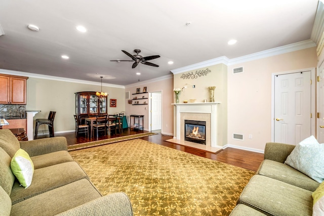 living area featuring a fireplace with flush hearth, dark wood-style flooring, visible vents, and crown molding