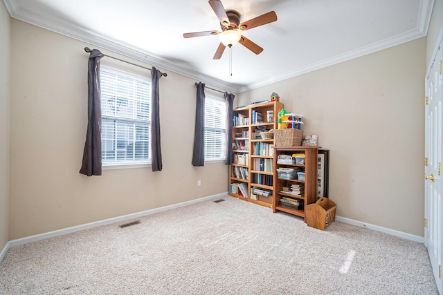 carpeted empty room featuring a ceiling fan, visible vents, crown molding, and baseboards