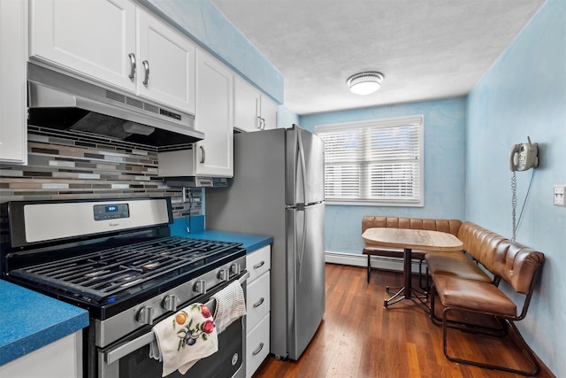 kitchen with under cabinet range hood, tasteful backsplash, stainless steel range with gas cooktop, white cabinets, and baseboard heating