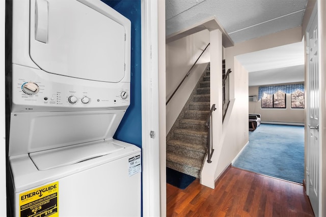 laundry room featuring wood finished floors, baseboards, a baseboard radiator, laundry area, and stacked washer and dryer