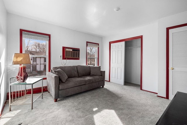 living area featuring carpet flooring, plenty of natural light, baseboards, and a wall mounted AC