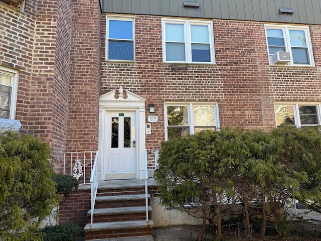 doorway to property featuring brick siding and cooling unit