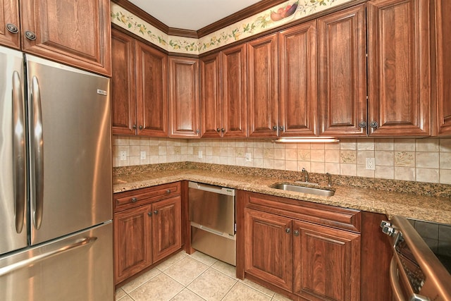 kitchen featuring appliances with stainless steel finishes, a sink, backsplash, and light tile patterned floors