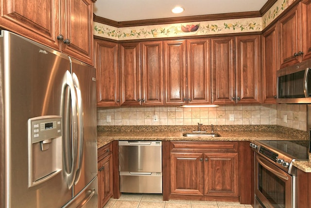 kitchen with appliances with stainless steel finishes, light tile patterned flooring, a sink, and tasteful backsplash