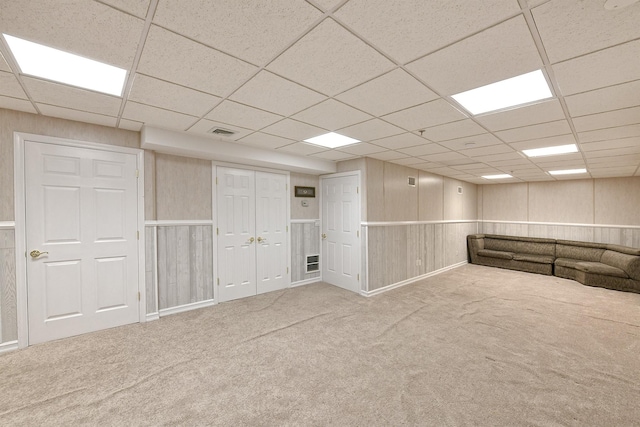 finished below grade area featuring a drop ceiling, carpet flooring, and visible vents