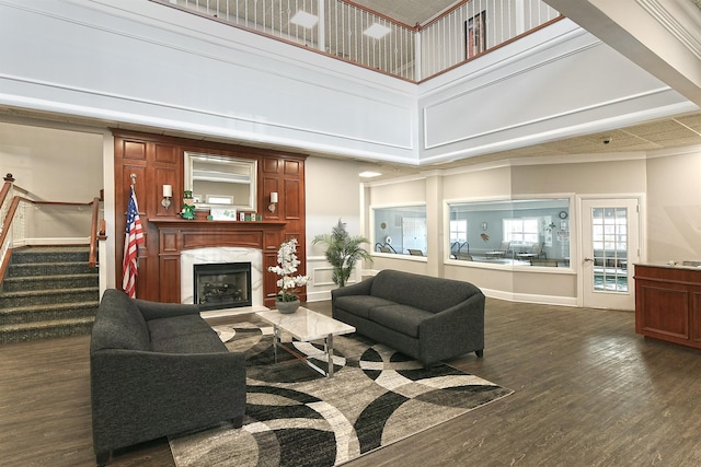 living area featuring stairs, a high ceiling, dark wood-style flooring, and a high end fireplace